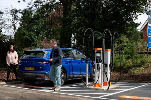 A man and a women getting out of the electric car ready to charge their car at a Osprey EV charger