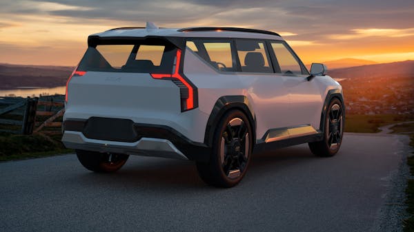 Kia EV9 electric SUV parked on a road overlooking a town