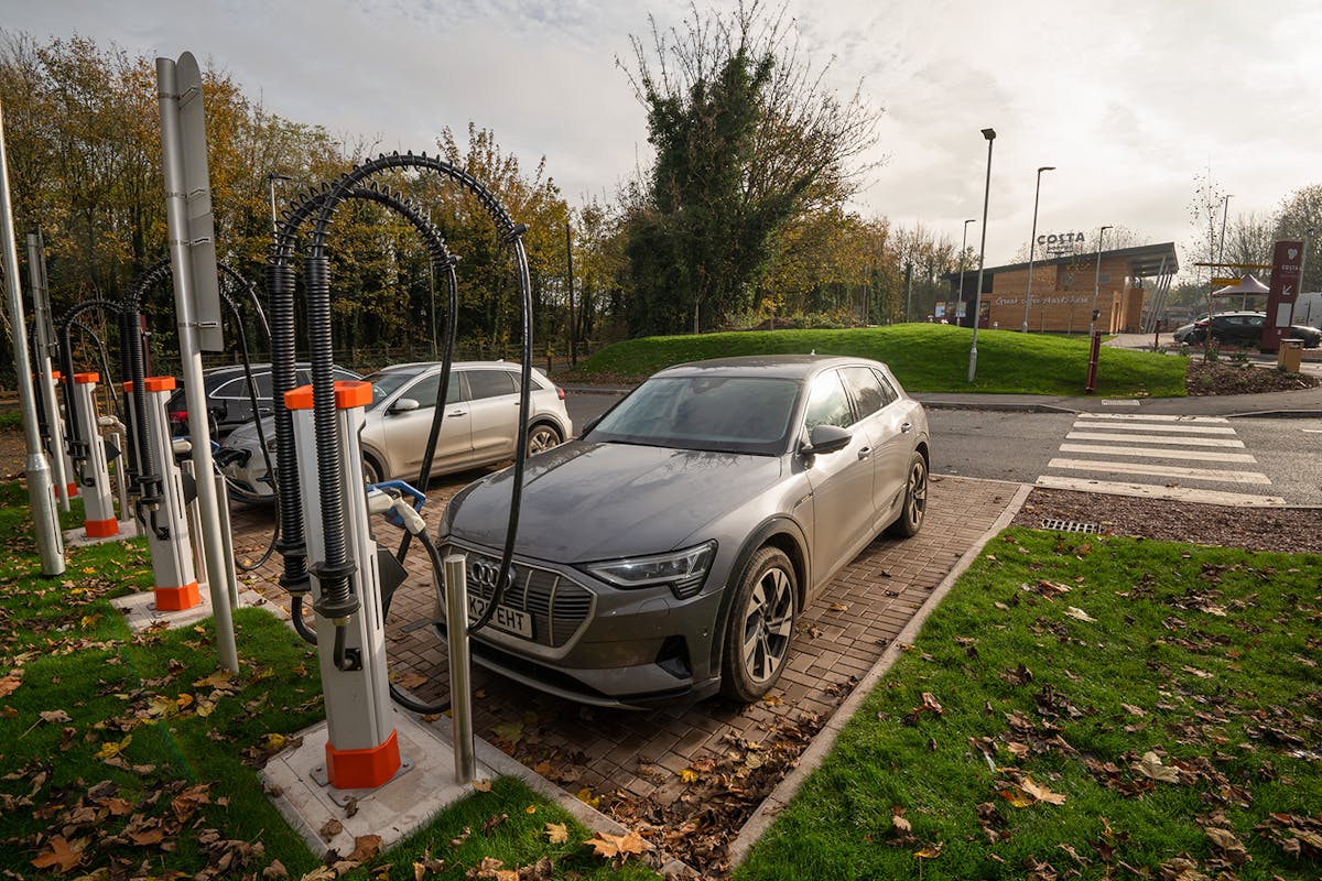 Electric cars plugged in to an ultra-rapid Osprey EV charging station by a Costa Coffee