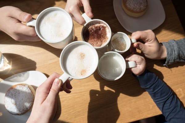 Overhead shot of coffee mugs being held by various hands of different ages