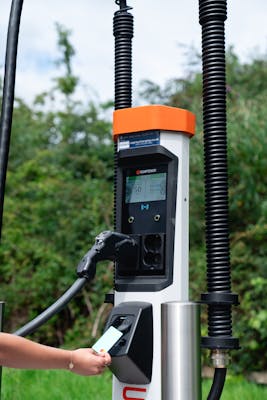 A person presenting their card on the card reader at a Osprey EV rapid charger to pay for their cars charge.