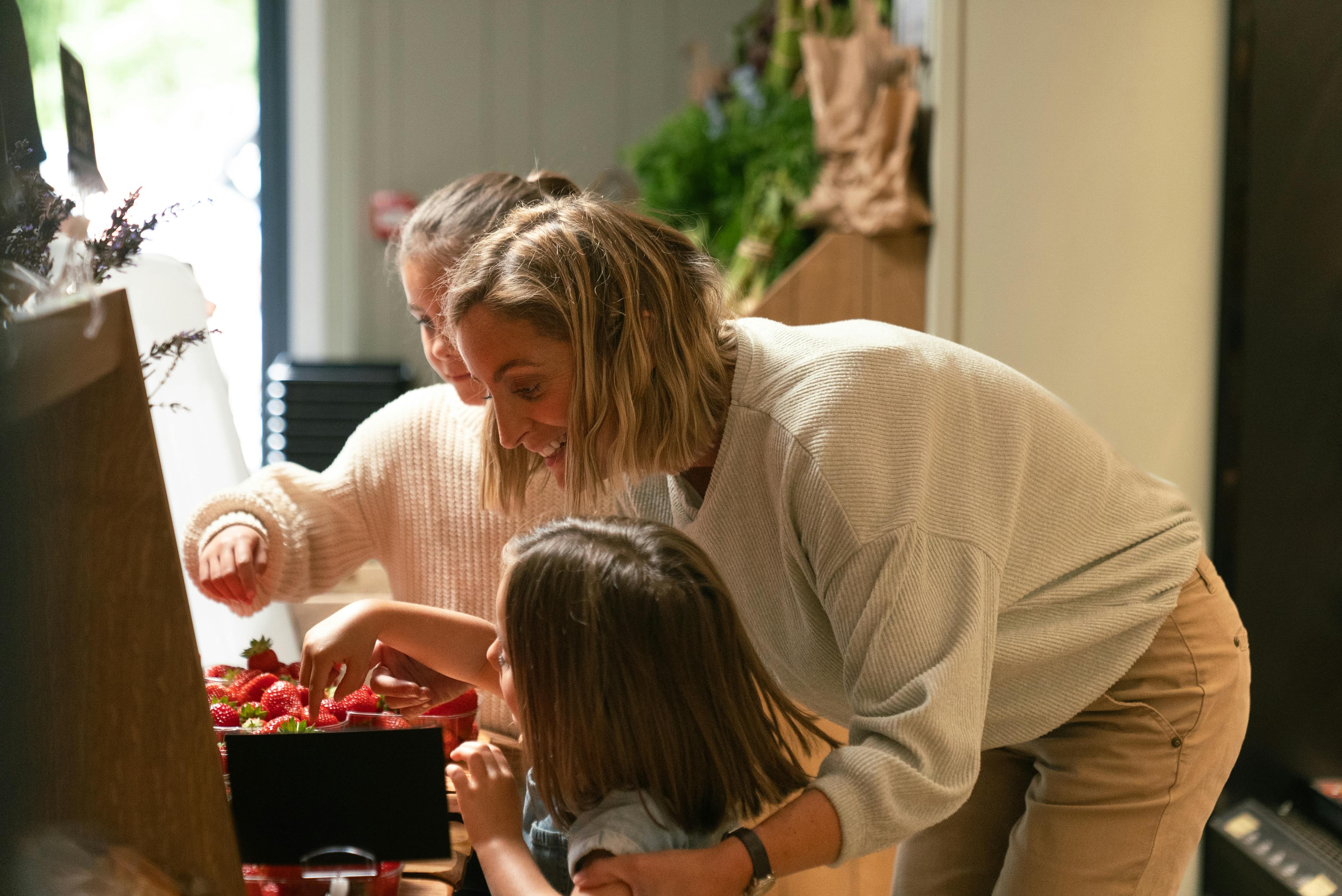 A women with her children taking a break eating strawberries while waiting for her electric car to charge at a Osprey EV charger.