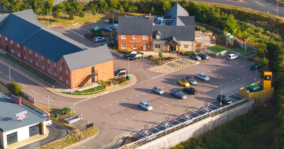 Aerial shot of Paisley Pear restaurant and hotel with 8-charger rapid charging hub in carpark.