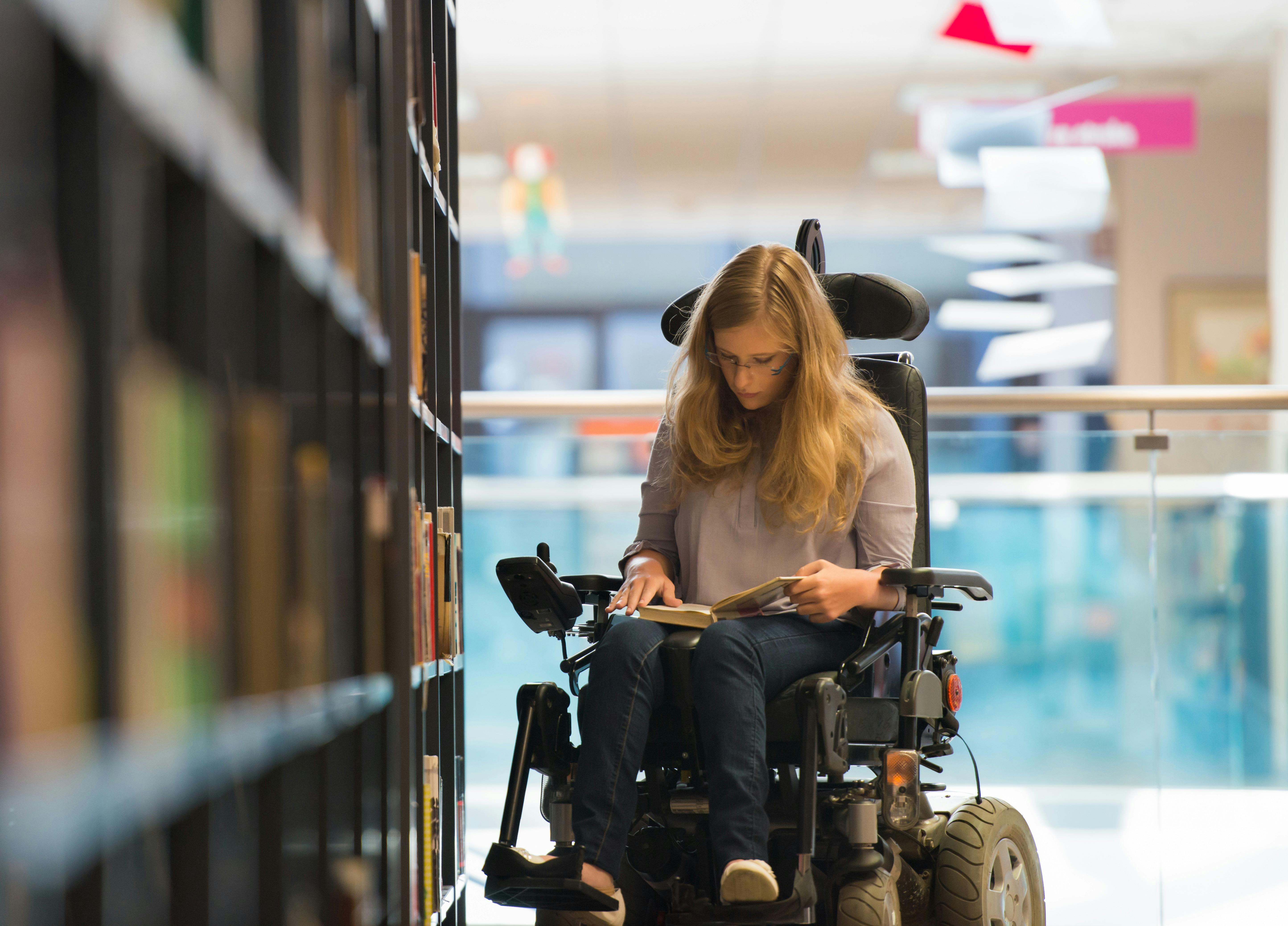 Student using an electric wheelchair in a library