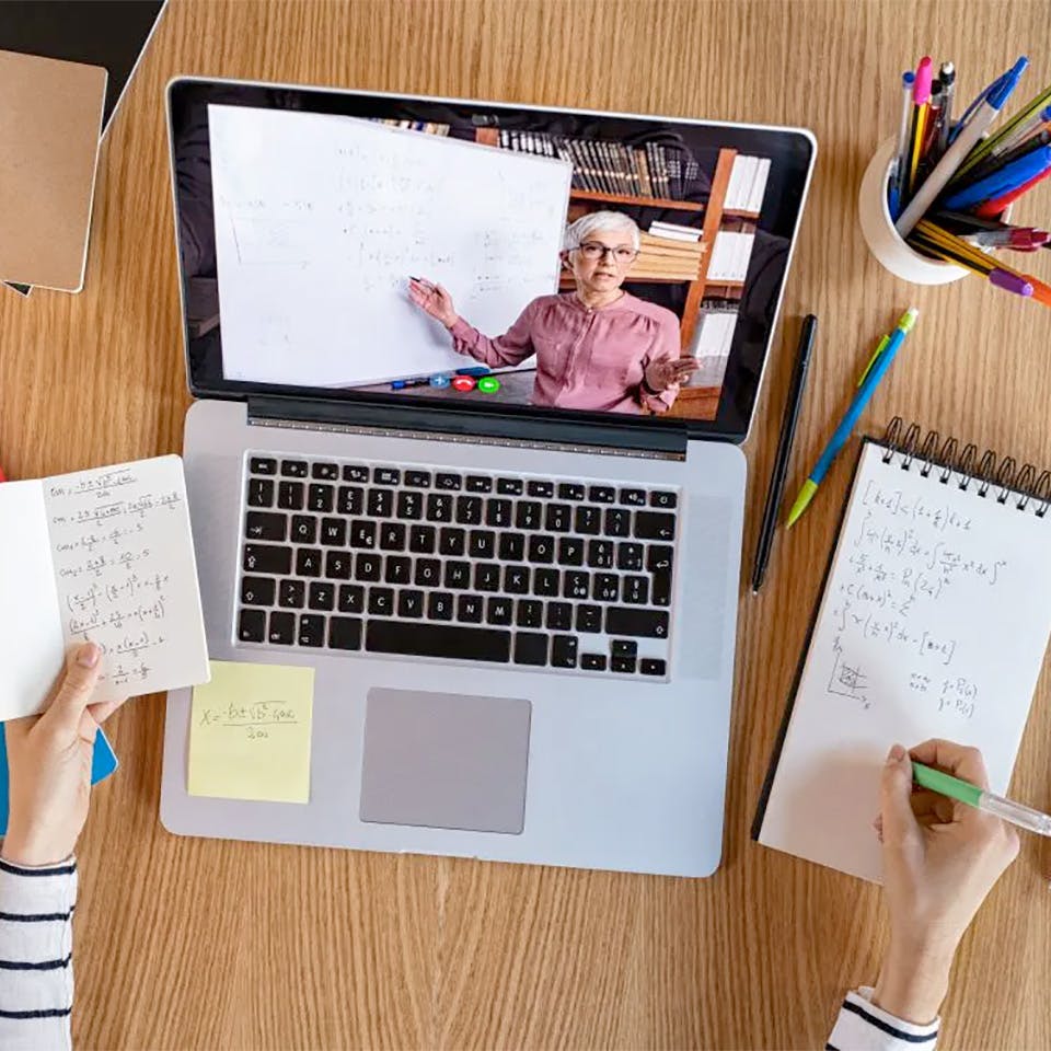 Student taking notes while on an online course.