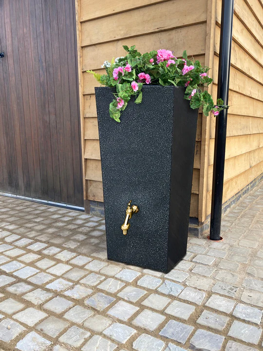 A photograph of a rain planter - a water tank with a space on top for planting flowers, and a bronze tap on the front.