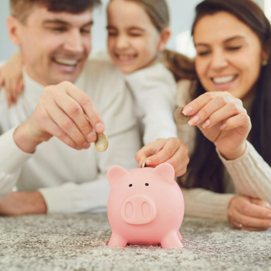 A mum dad and daughter all putting money into a piggybank