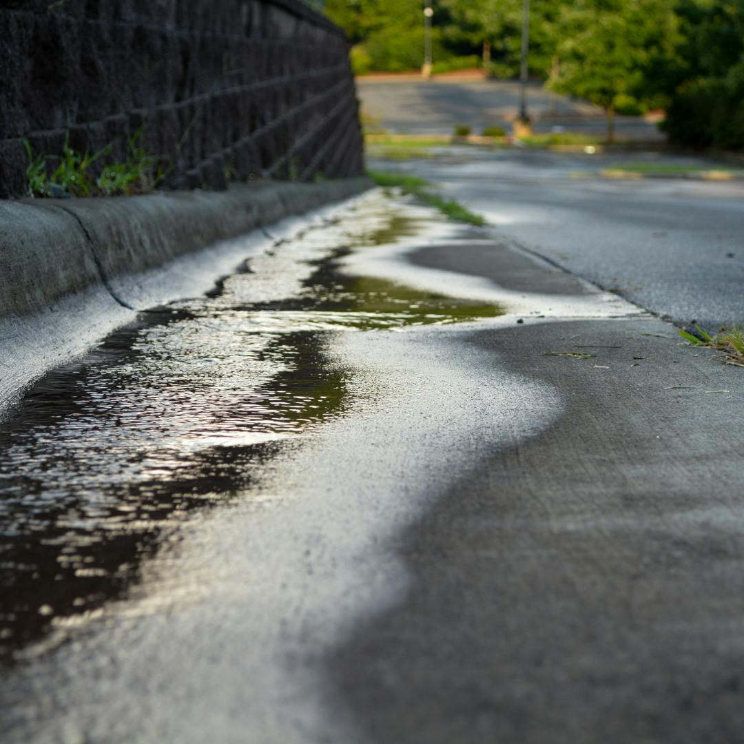 a road running downhill with surface water on the side of it