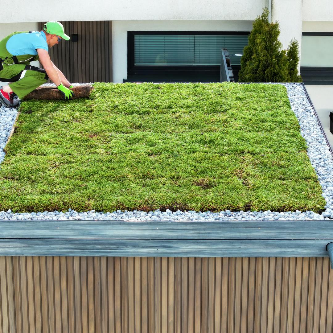 Someone fitting turf on what appears to be a garage roof