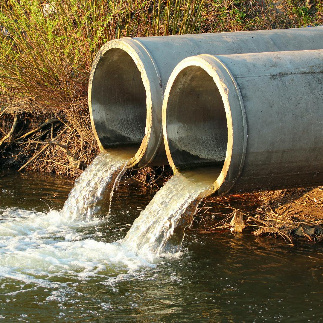 Two large pipes emptying water into a waterway