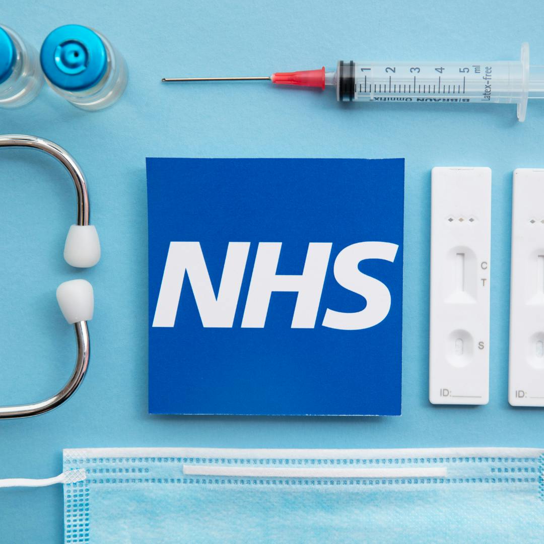 The NHS logo in the centre of a table with various medical equipment surrounding it