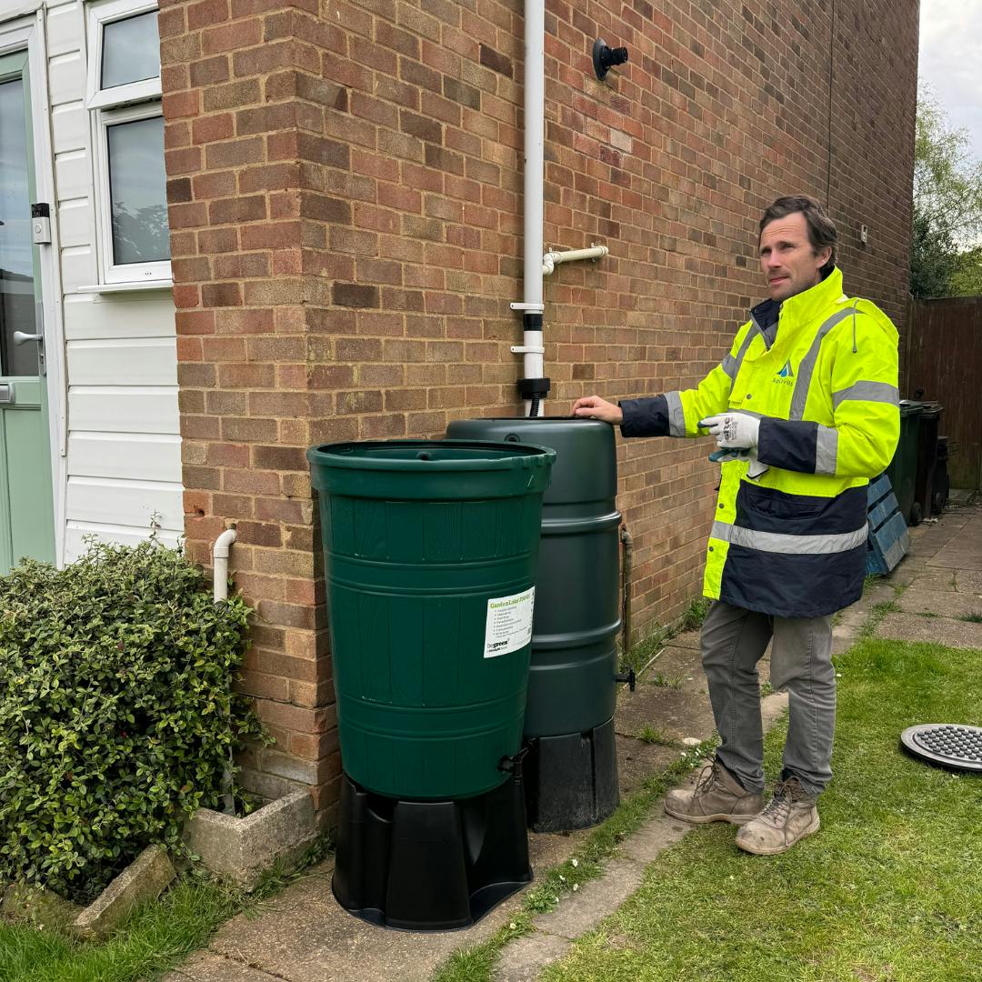 two green waters butts and installer stood by side of bricked property