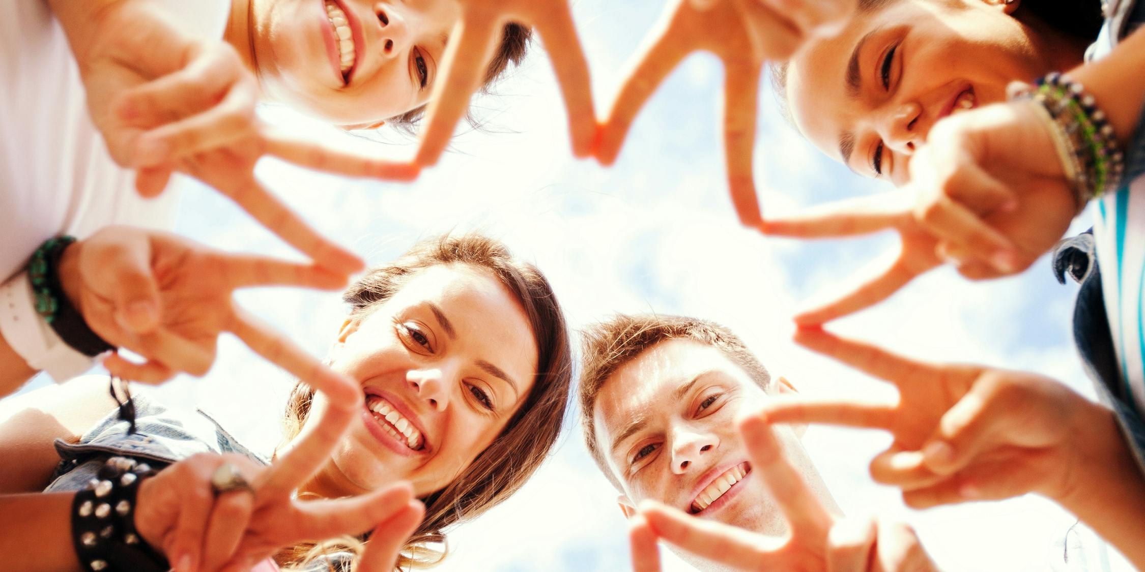 Young doing the 'peace sign' and connecting their fingers to form a circular star