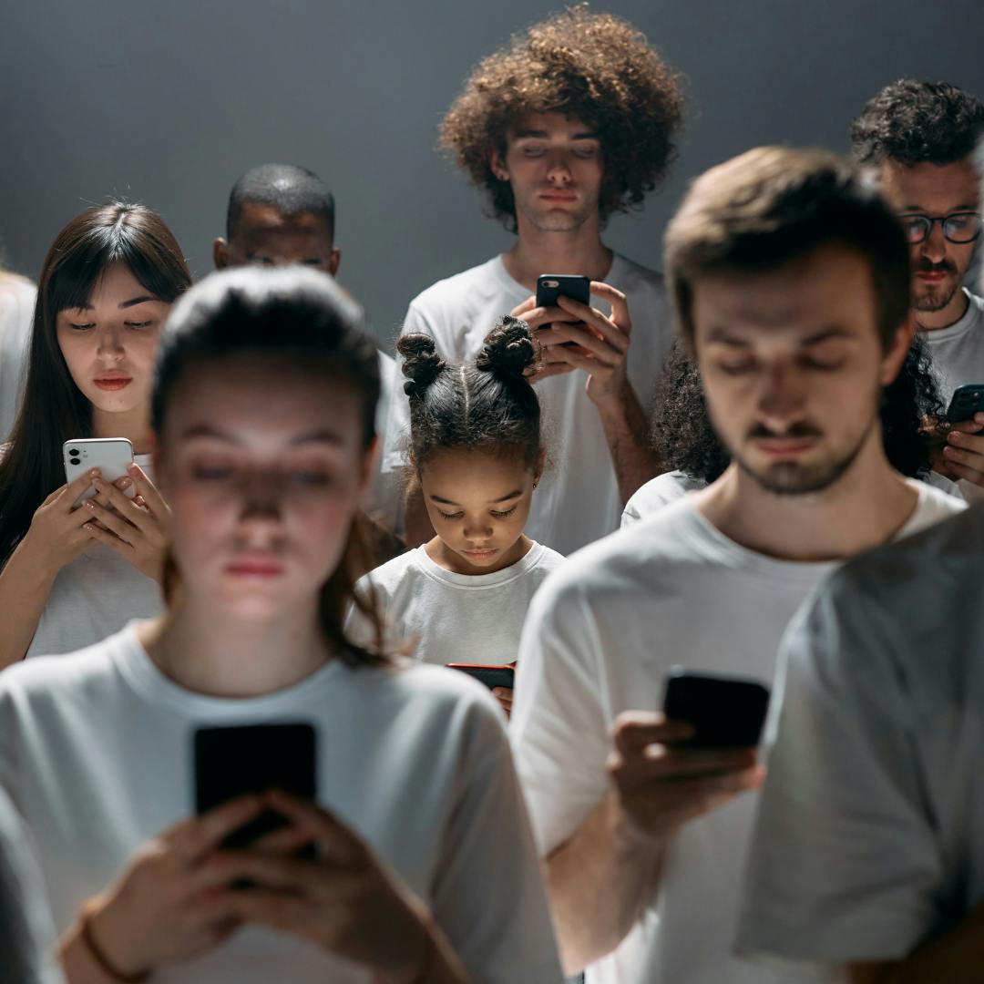 Young people of varying ages in white t-shirts all looking down at their phones