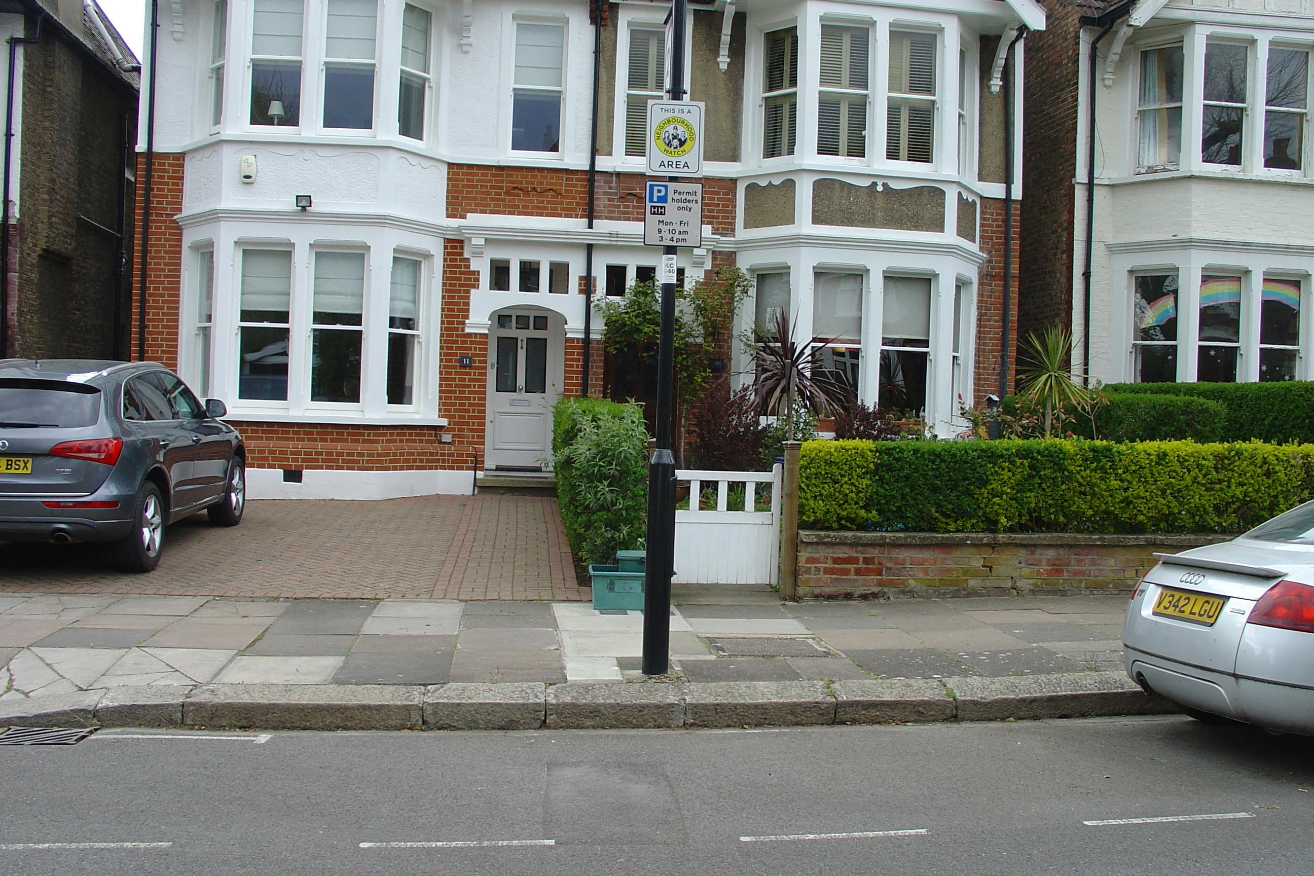 a grey car is parked in front of terraced housing on a front garden which is paved with bricks