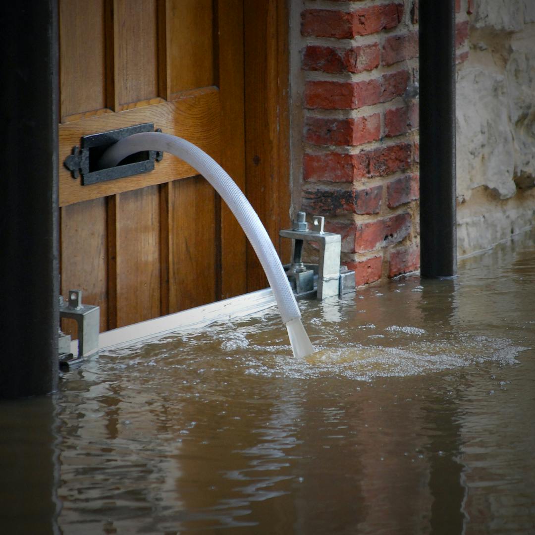 Water being pumped through a letterbox into a flooded street