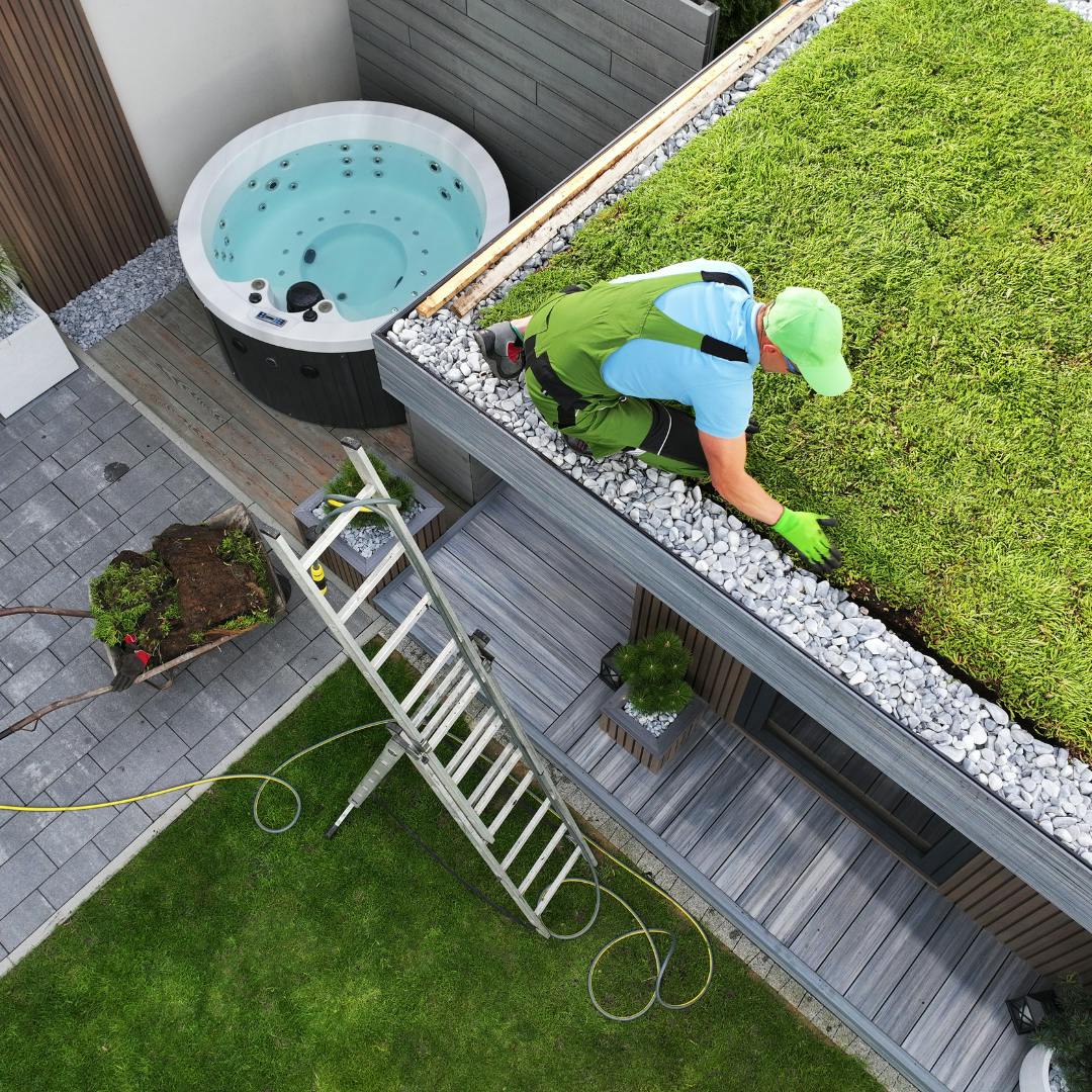 Aerial shot of a man putting down grass on the roof of a garage