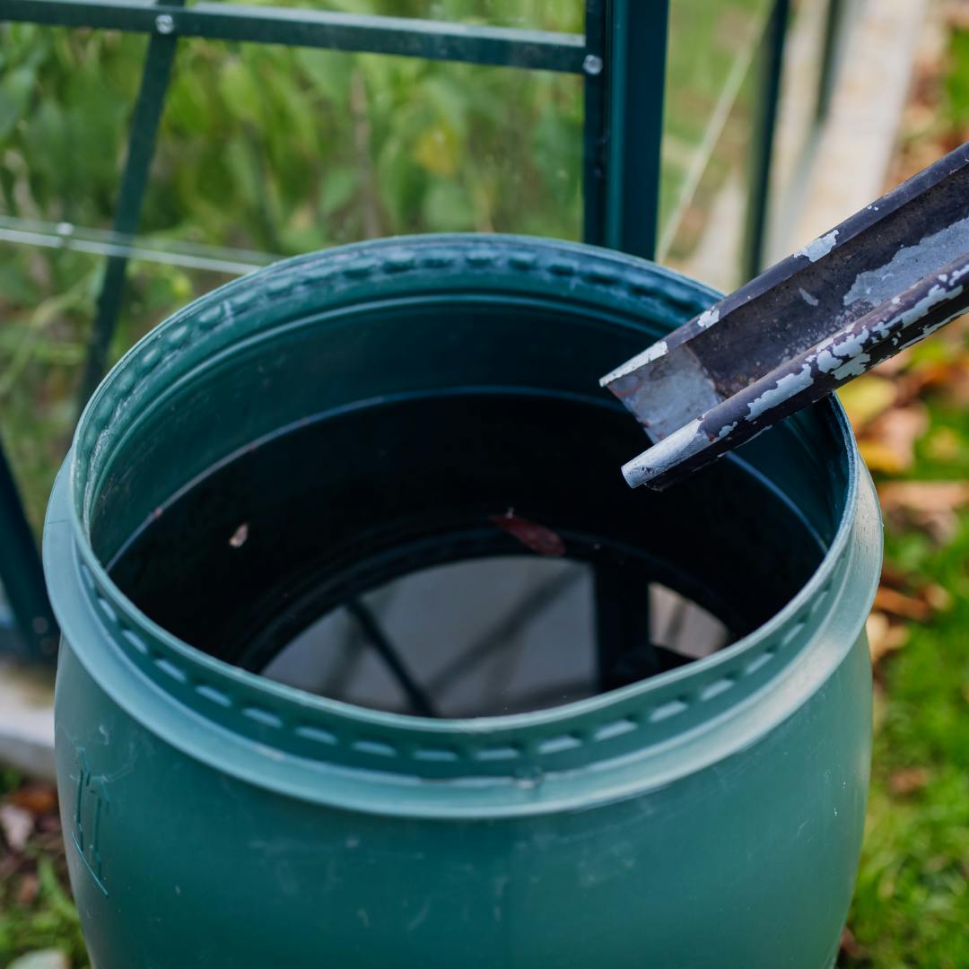 An open-top water butt with a downspout going into the opening