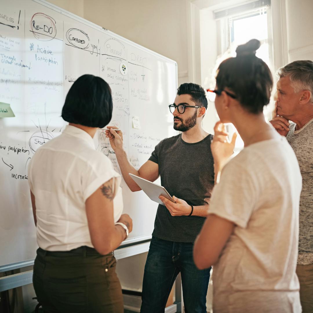 People discussing something next to a whiteboard