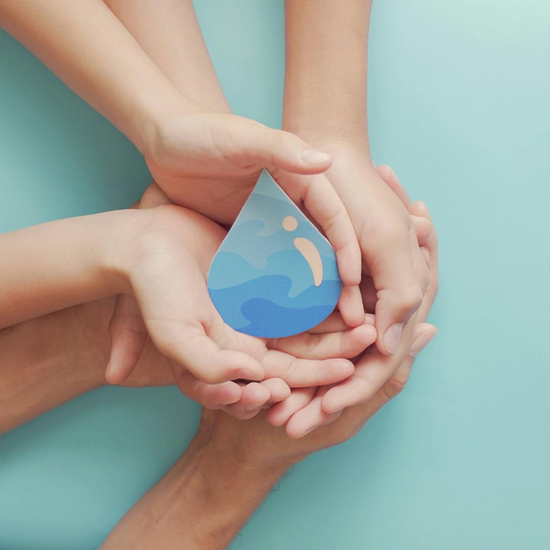 hands cupping a paper water drop on a blue background