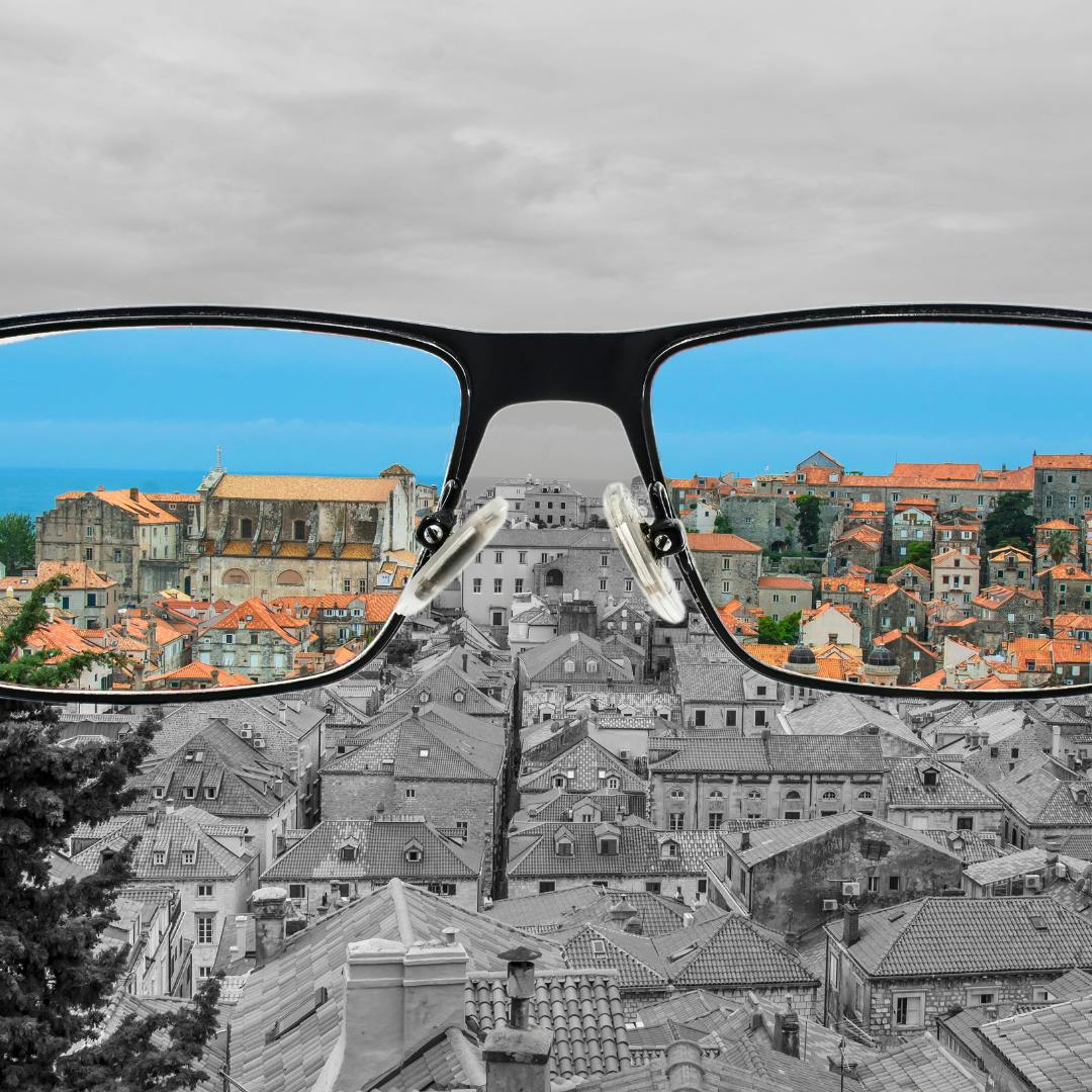 A picture of a city with glasses in front. The city is black and white but through the glasses its is coloured