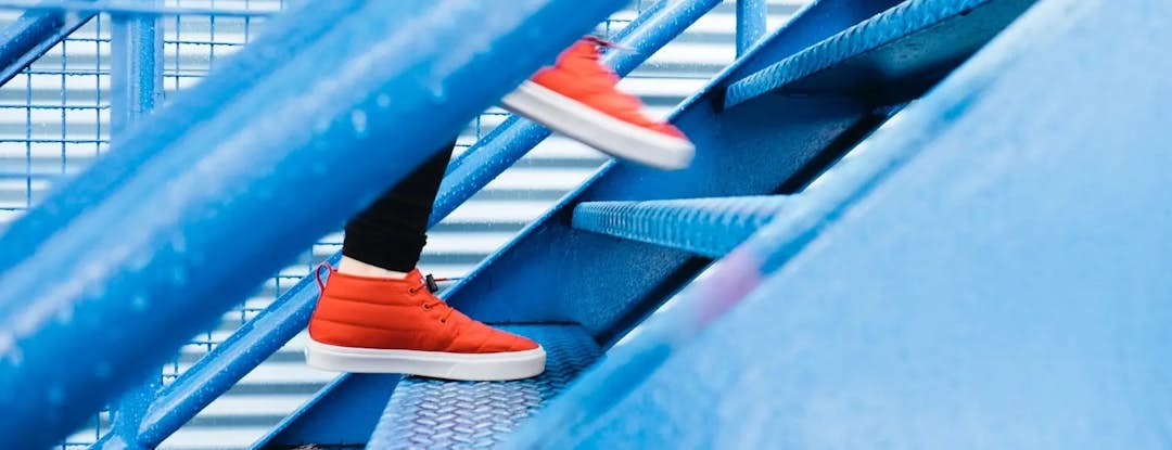 Escaleras de metal azul con subir y usar zapatos rojos.