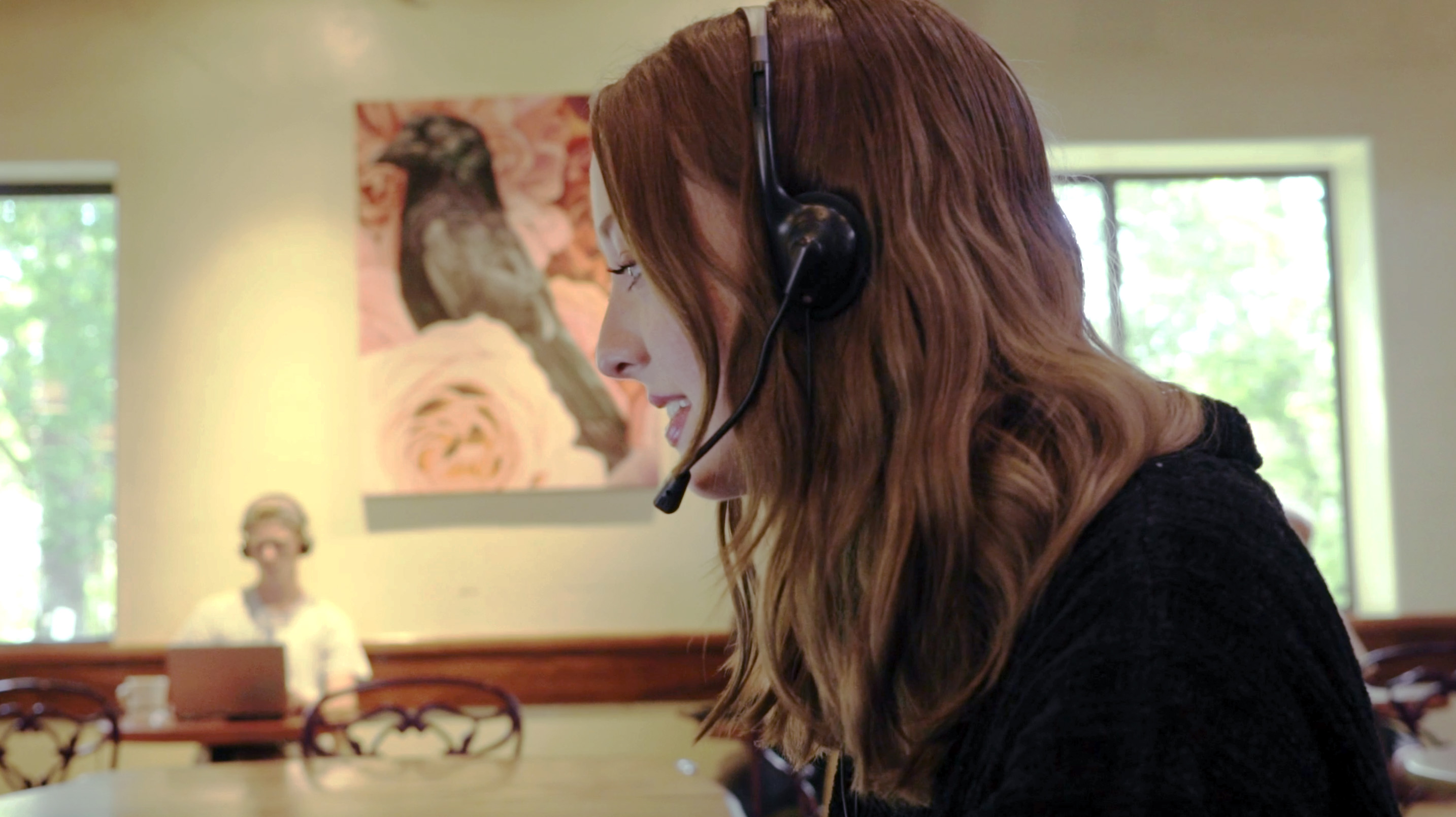 A redheaded woman's side profile as she works wearing a headset.