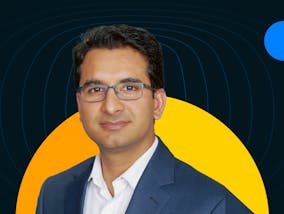 Anshul Verma, founder of Cynoteck, wears a suit and glasses against a yellow-orange half-circle.