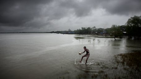 A BOY PLAYS FOOTBALL IN BANGLADESH, PADMA PAKUR, KHULNA DIVISION, 2009