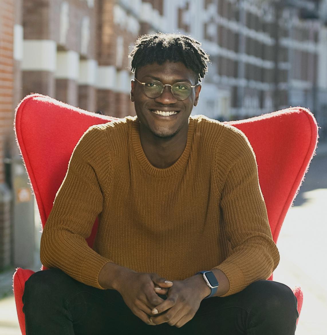 Photo of Ovie sitting on a red chair smiling