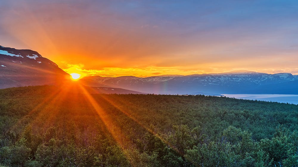 Vacker solnedgång över grönska och berg