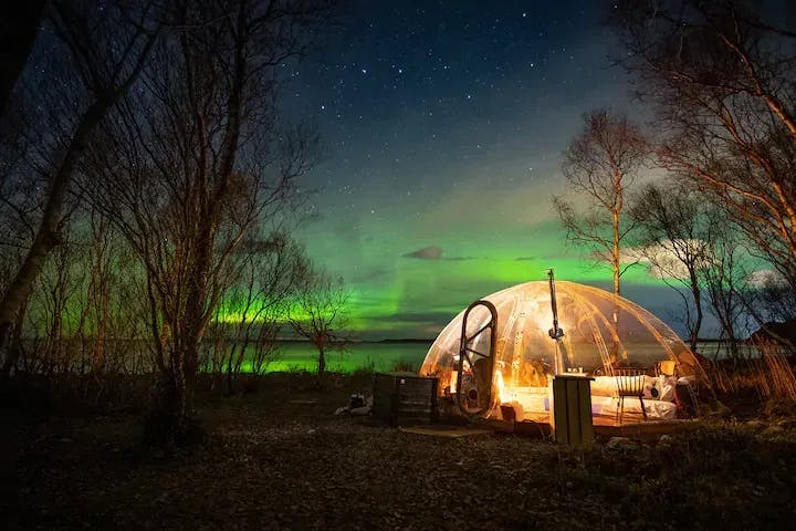 glassdome i norsk natur med nordlys i horisonten