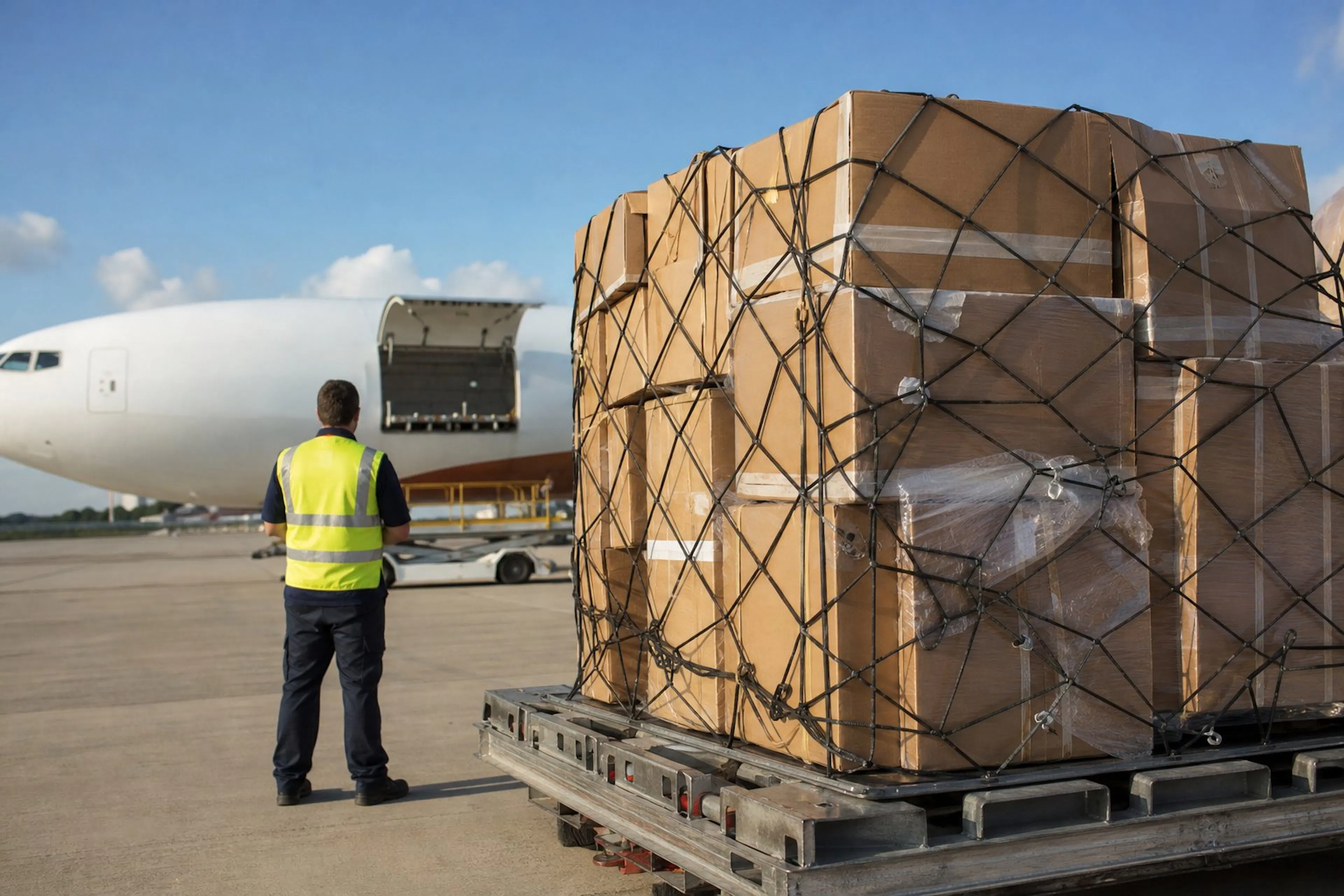 Parcels on an air freight pallet beside a cargo aircraft