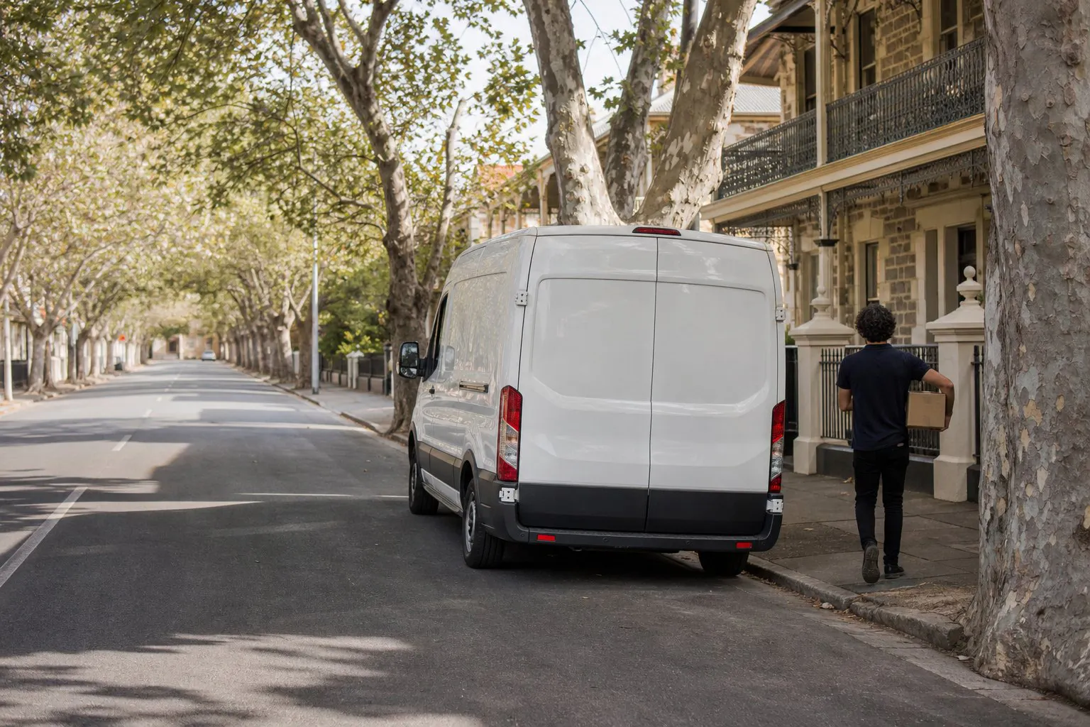 Courier carrying a parcel past bluestone villas in Adelaide