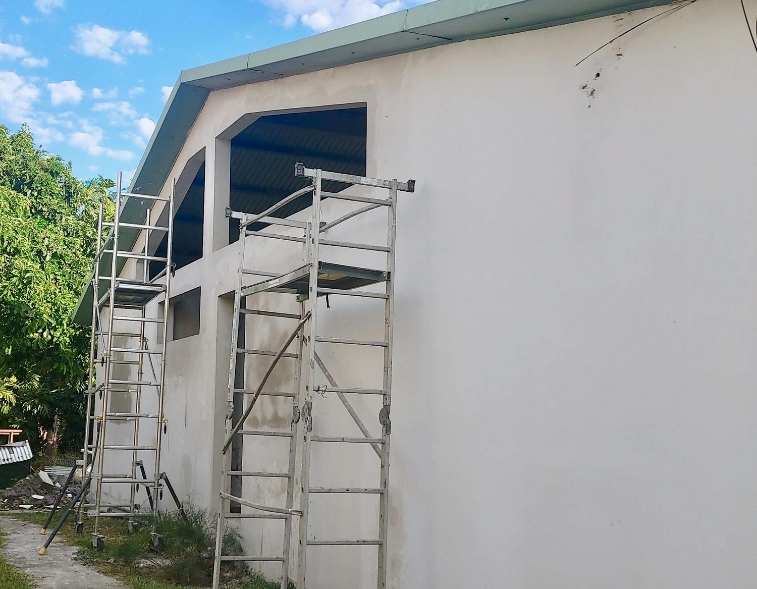 La façade d'une maison en rénovation avec des ouvertures sur la partie supérieure, et un échafaudage installé devant.