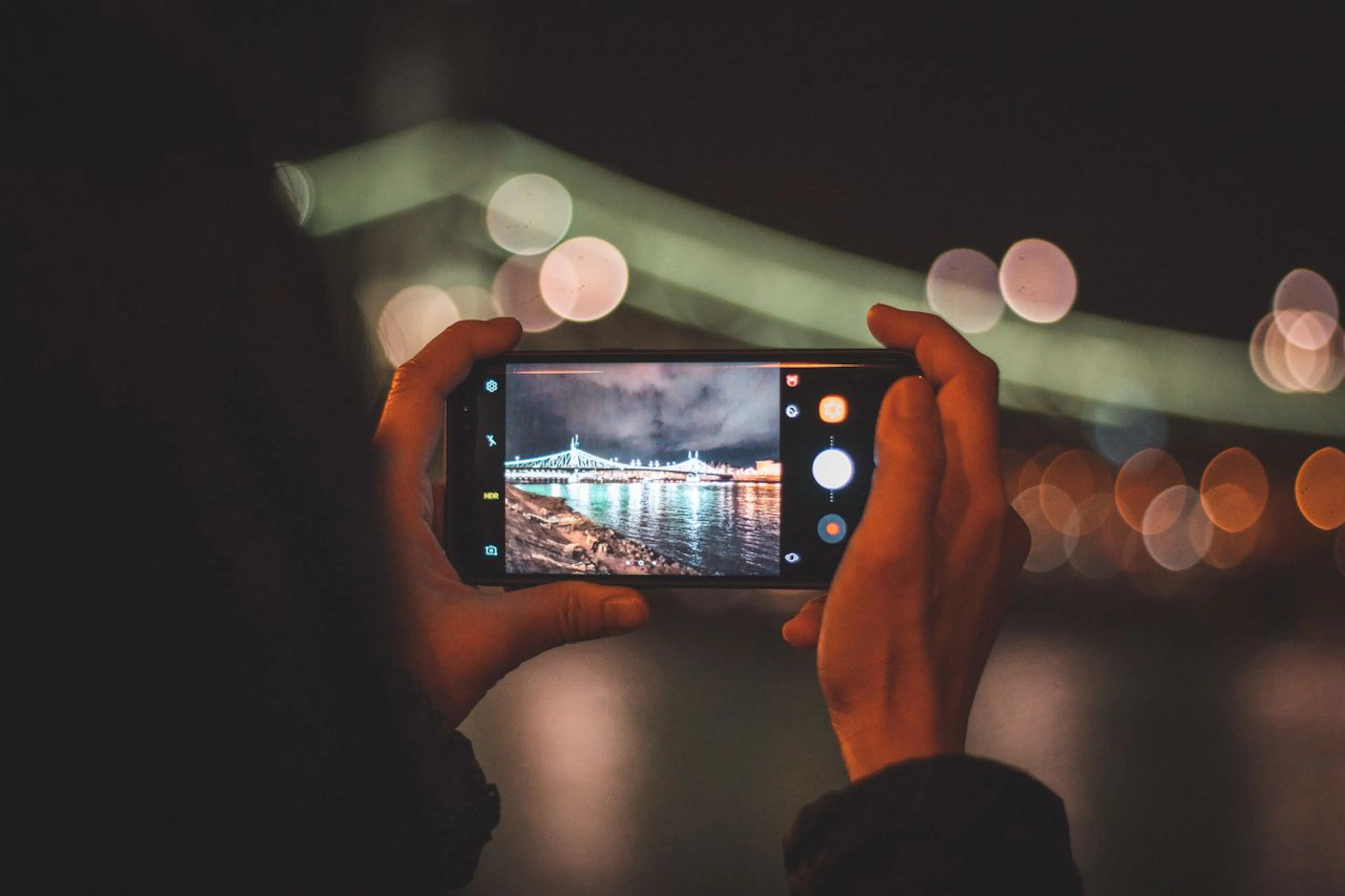 photographer taking a photo of a bridge at night