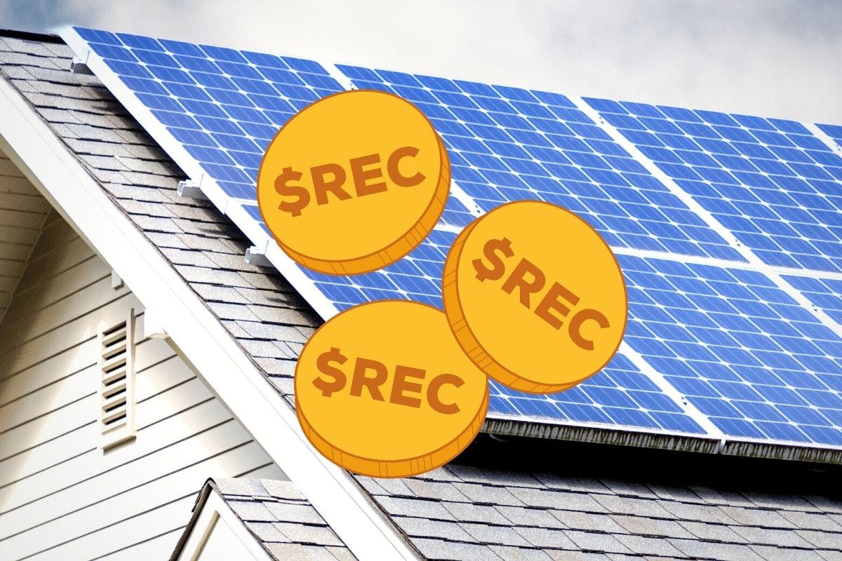 Three gold coins marked with $REC representing Solar Renewable Energy Credits lie atop blue solar panels, installed on the grey roof of a white house.