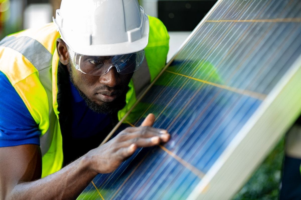Solar panel technician inspecting the surface of a solar panel, checking to make sure the solar panels are working.