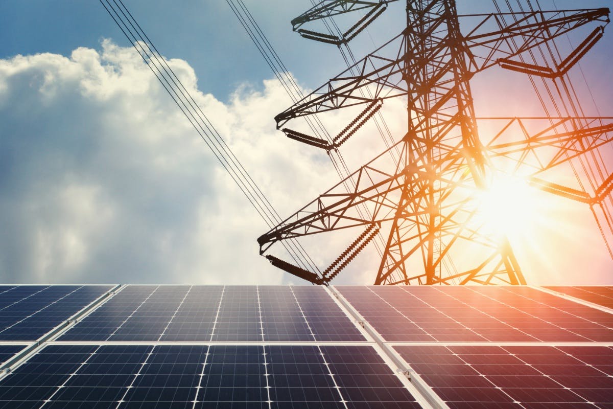 Solar panels below power lines, showing solar power and the grid working together to become a smart grid.