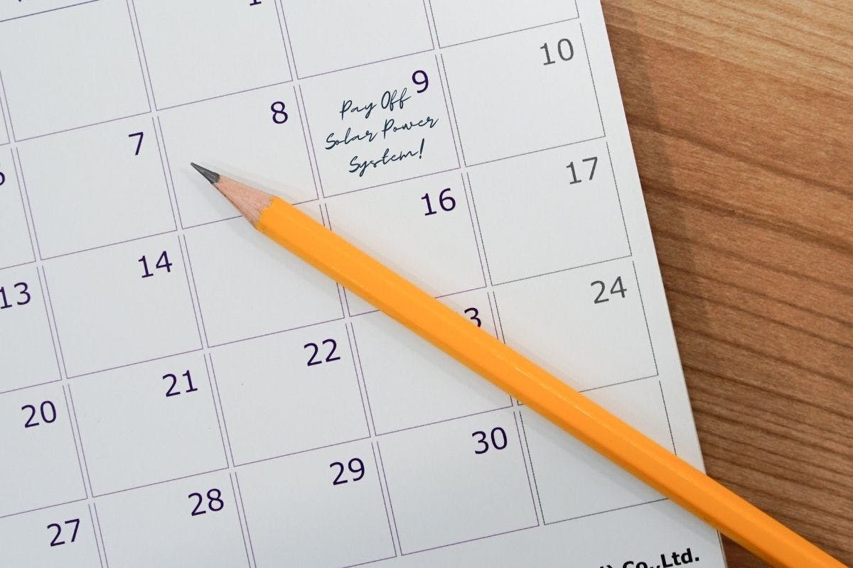 yellow pencil on calendar with pay off solar power system written on the ninth day of the month