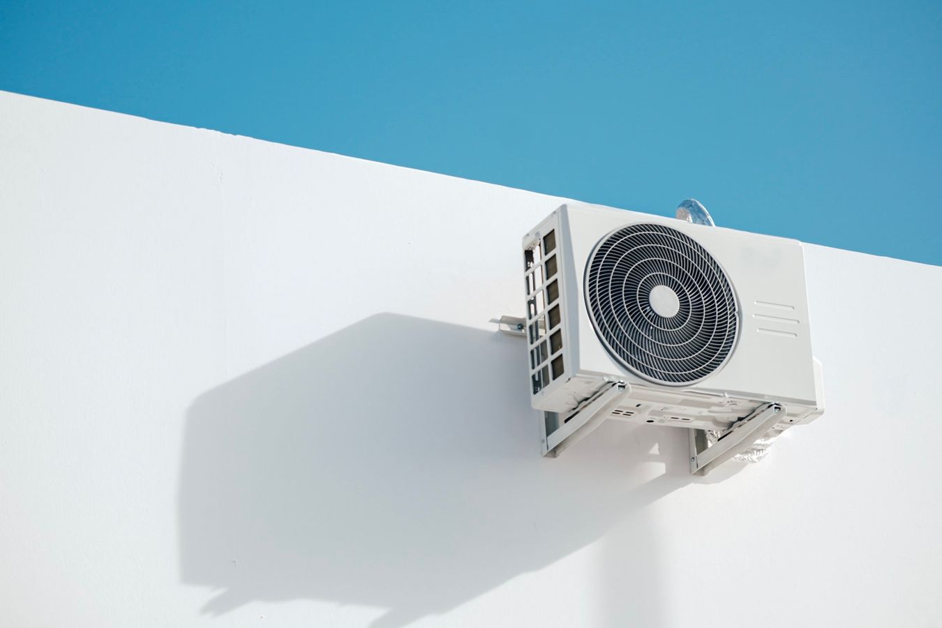 Exterior air conditioner unit mounted near the top of a wall.