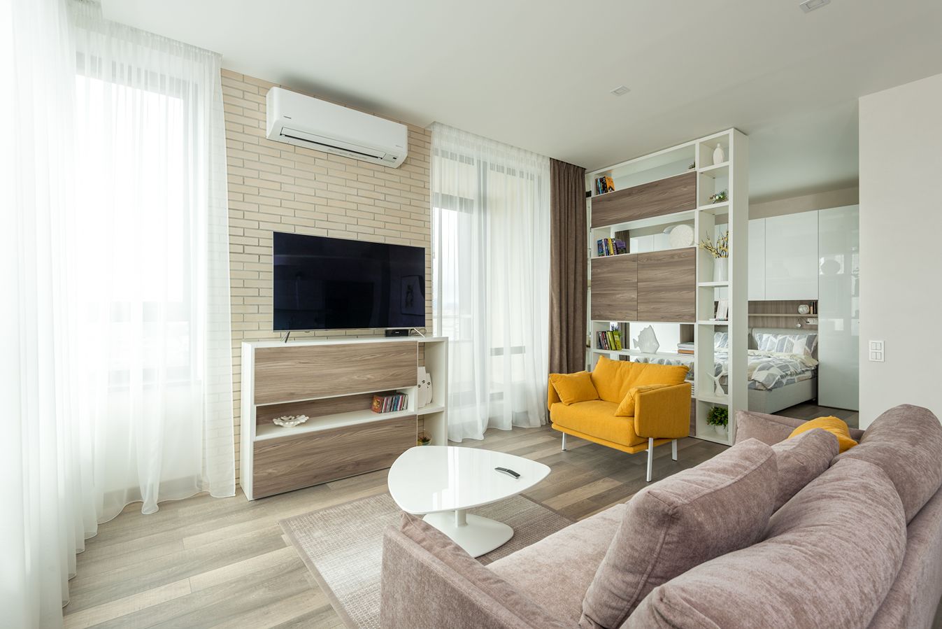A mini-split heat pump on the wall of a well-lit living room.