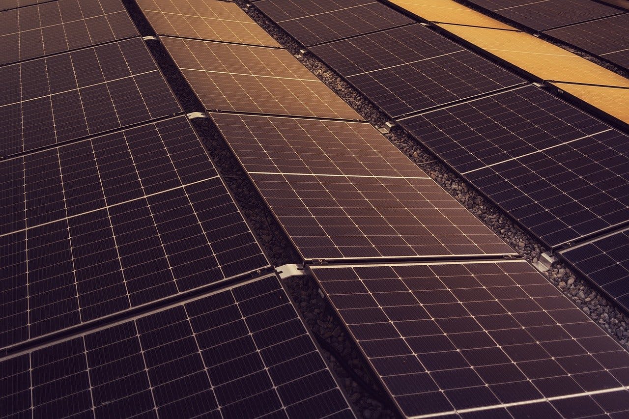 Solar panels angled in two directions on a large rooftop.