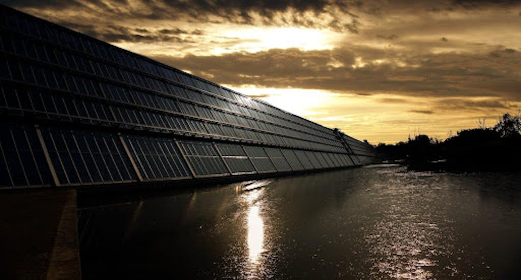 An array of solar panels with a sunset in the background