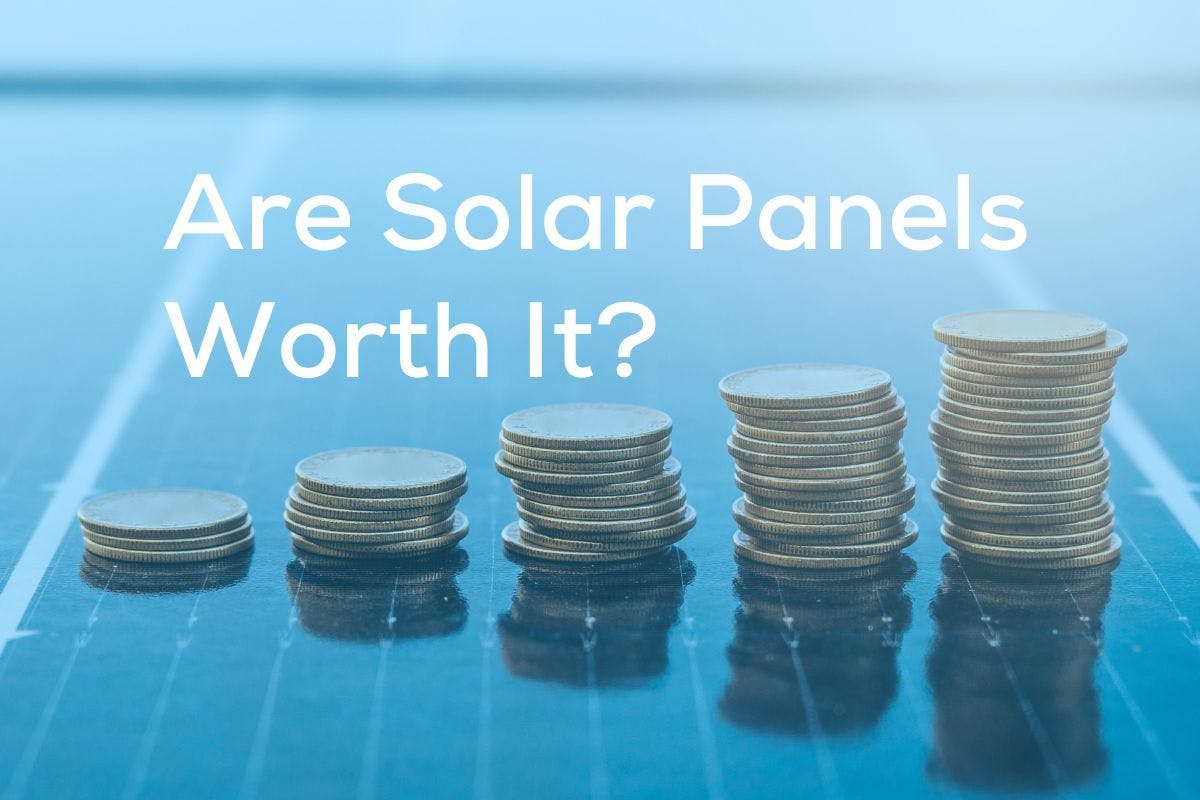 Stacks of coins increasing in size on a solar panel with the words, Are Solar Panels Worth It? above them.
