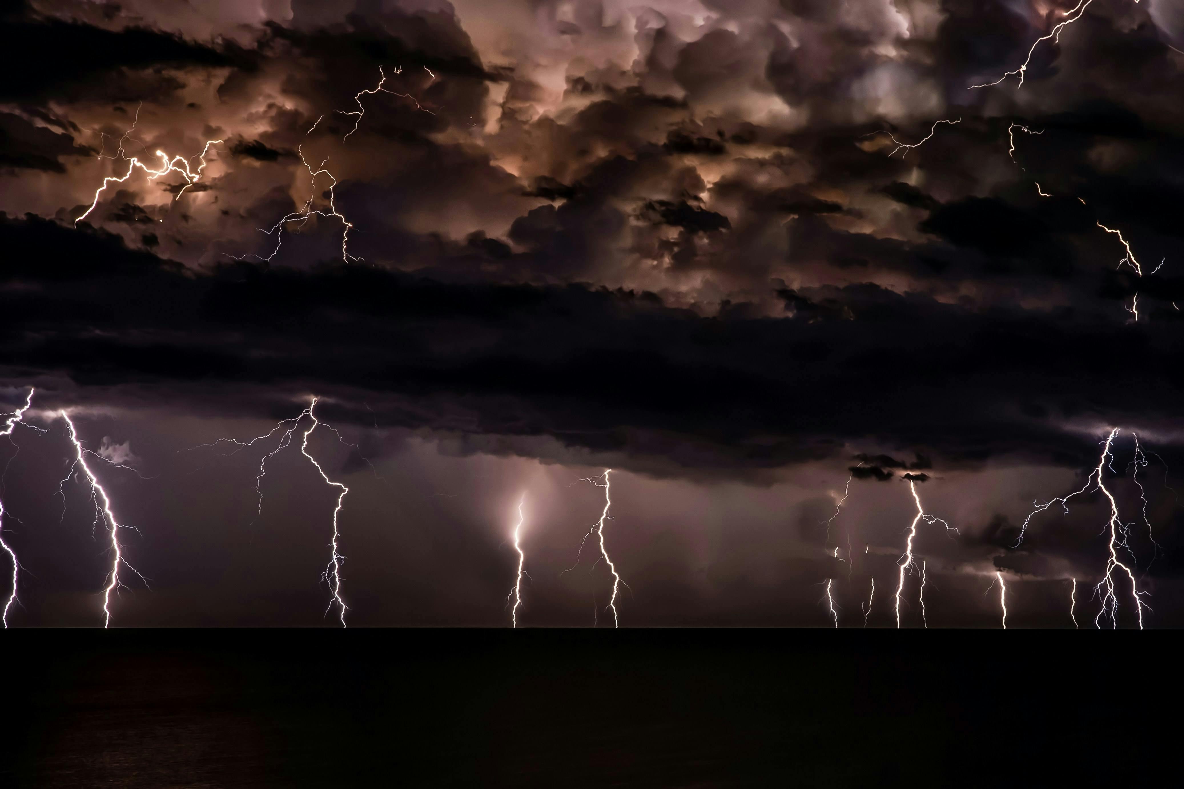 Multiple lightning strikes from dark clouds at night.