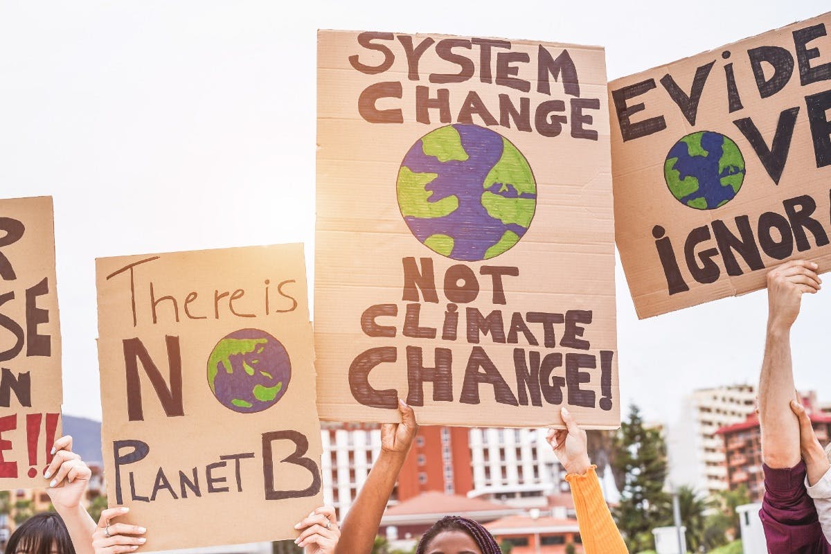 People holding up protest signs about climate change, the earth, environmental concerns, global warming, and more.