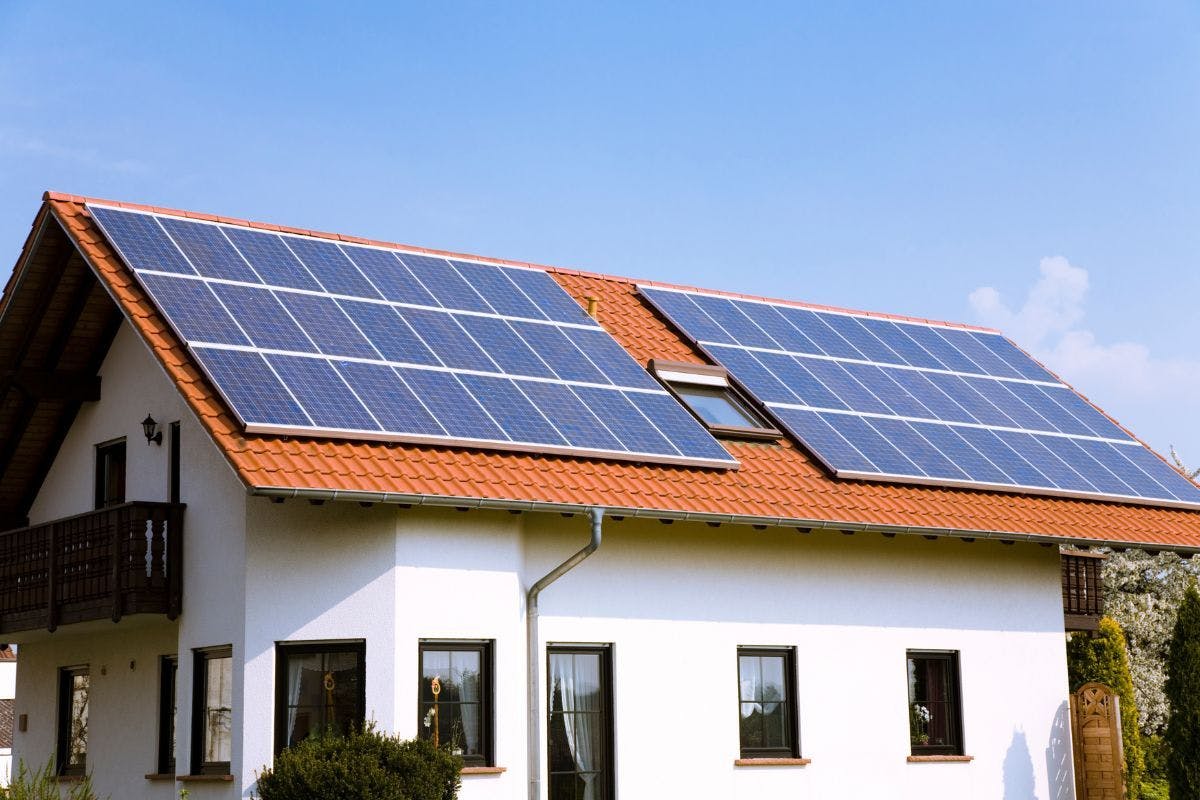 Solar panels on a white house with a tile roof.