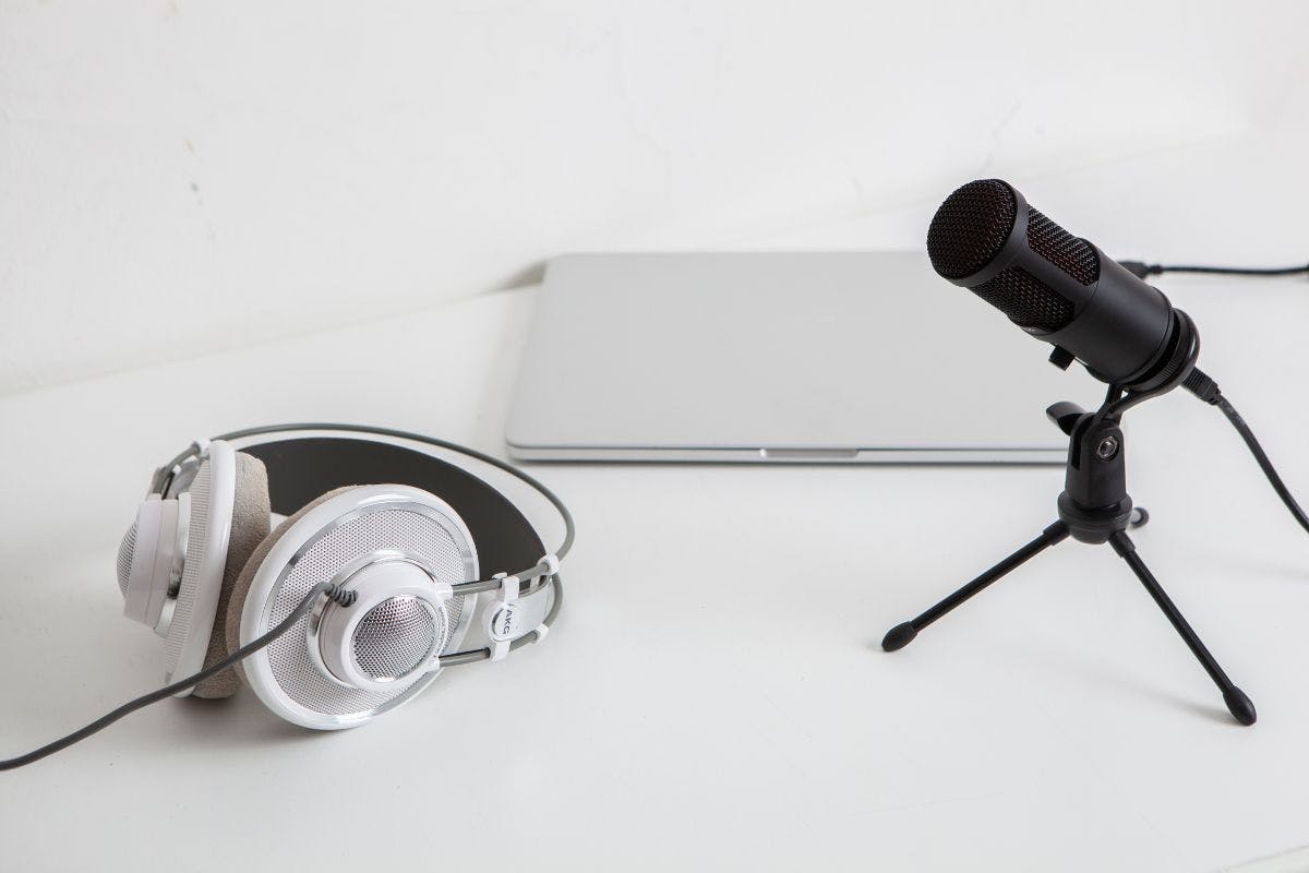 Podcast microphone, headphones, and a laptop on a white background.