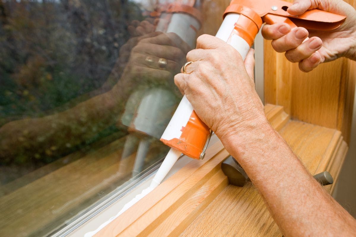Someone applying caulk to a window seal.